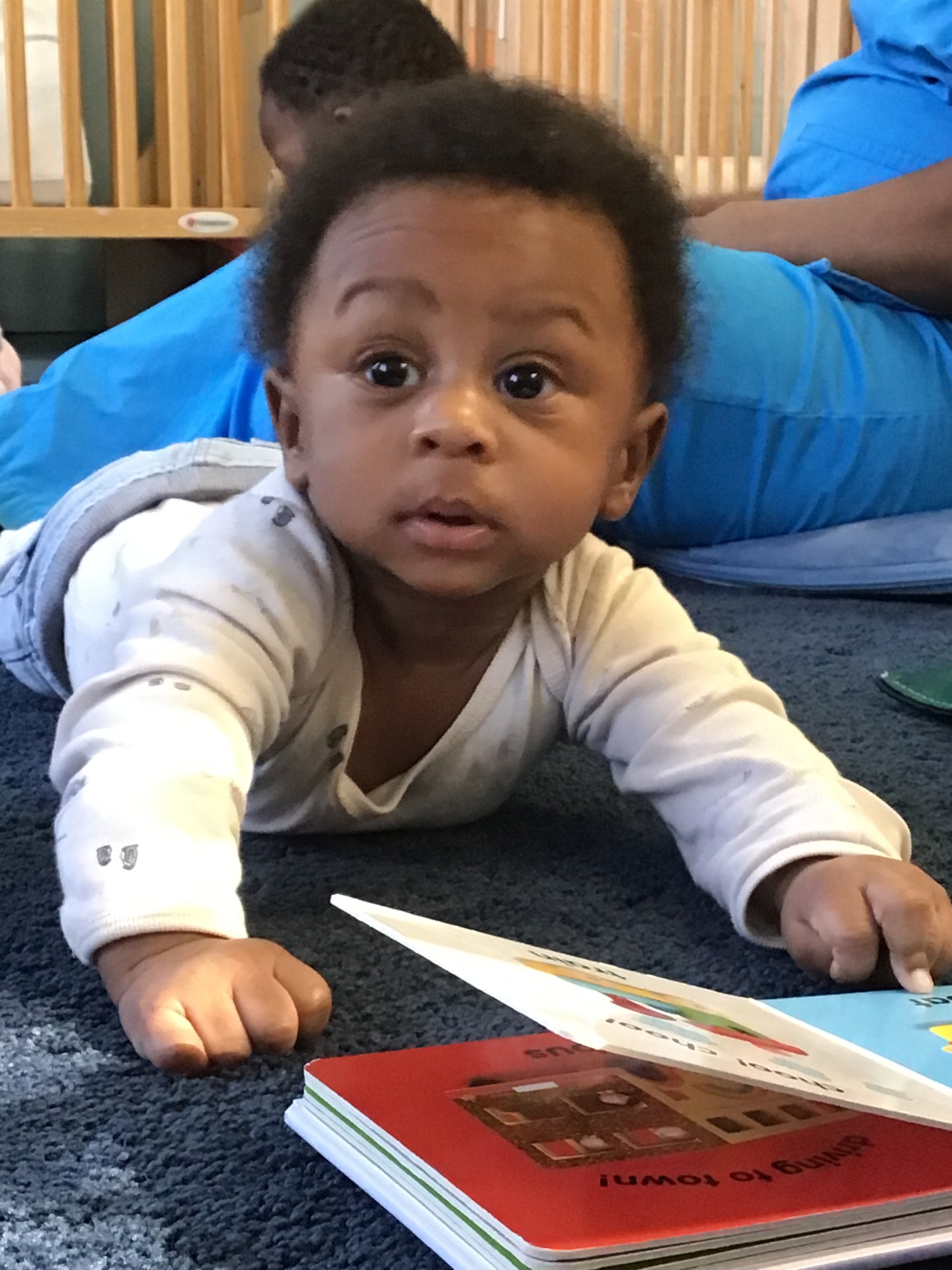 A curious infant is crawling on a blue carpet