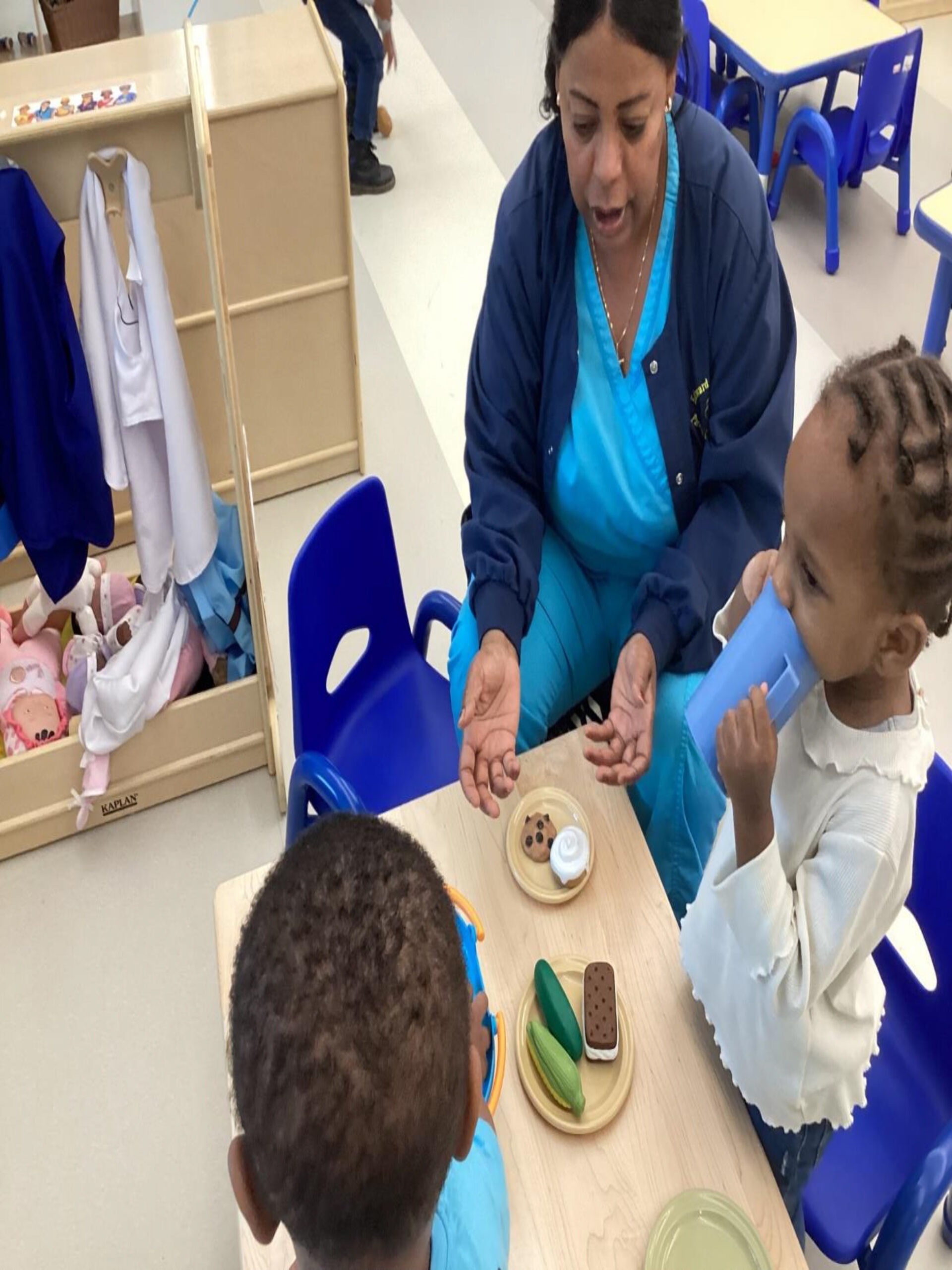 A caregiver engages two young children in a play-based learning activity